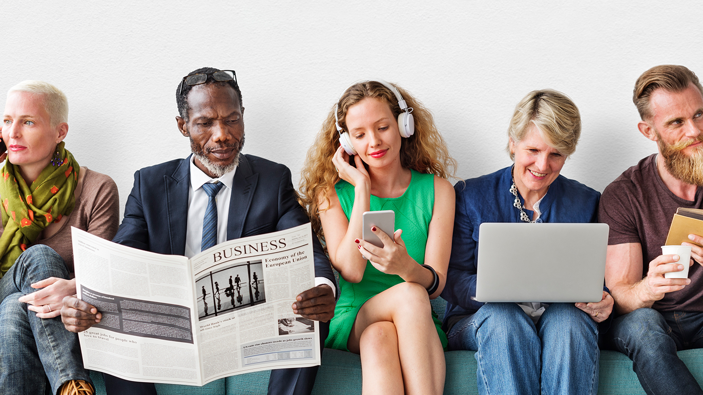 5 people of different gender, geographical origin and age sitting side by side while entertaining themselves by reading, listening to music or calling