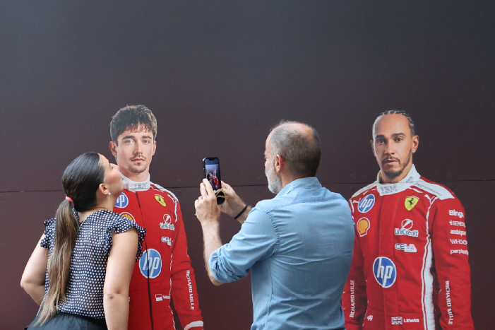 A man taking a picture of a woman with Ferrari F1 drivers Charles Leclerc and Lewis Hamilton