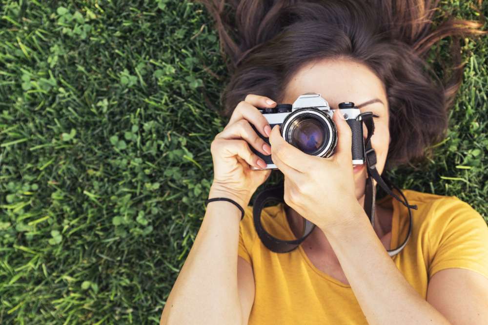 Smiling young woman using a camera to take photo. Smiling young woman using a camera to take photo at the park.